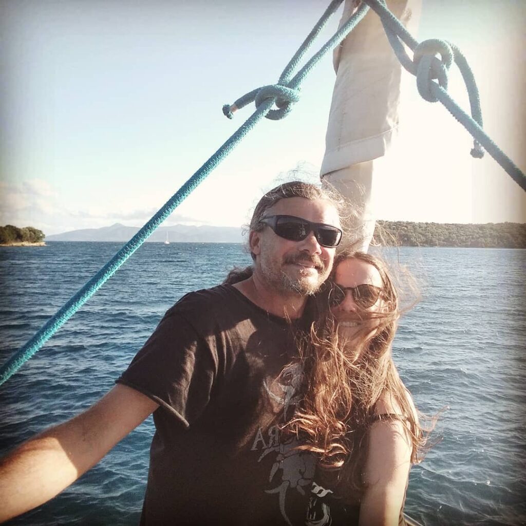 Couple in the wind on the bow of their sailboat