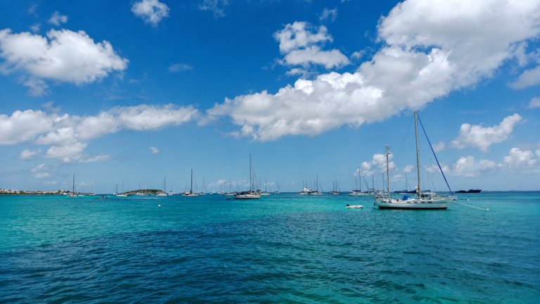 Sailboats anchored in a turquoise bay in St. Maarten under a bright Caribbean sky.