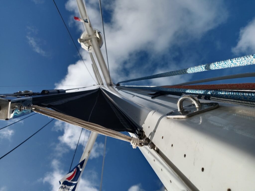 View along a sailboat mast resting on the deck during maintenance work.