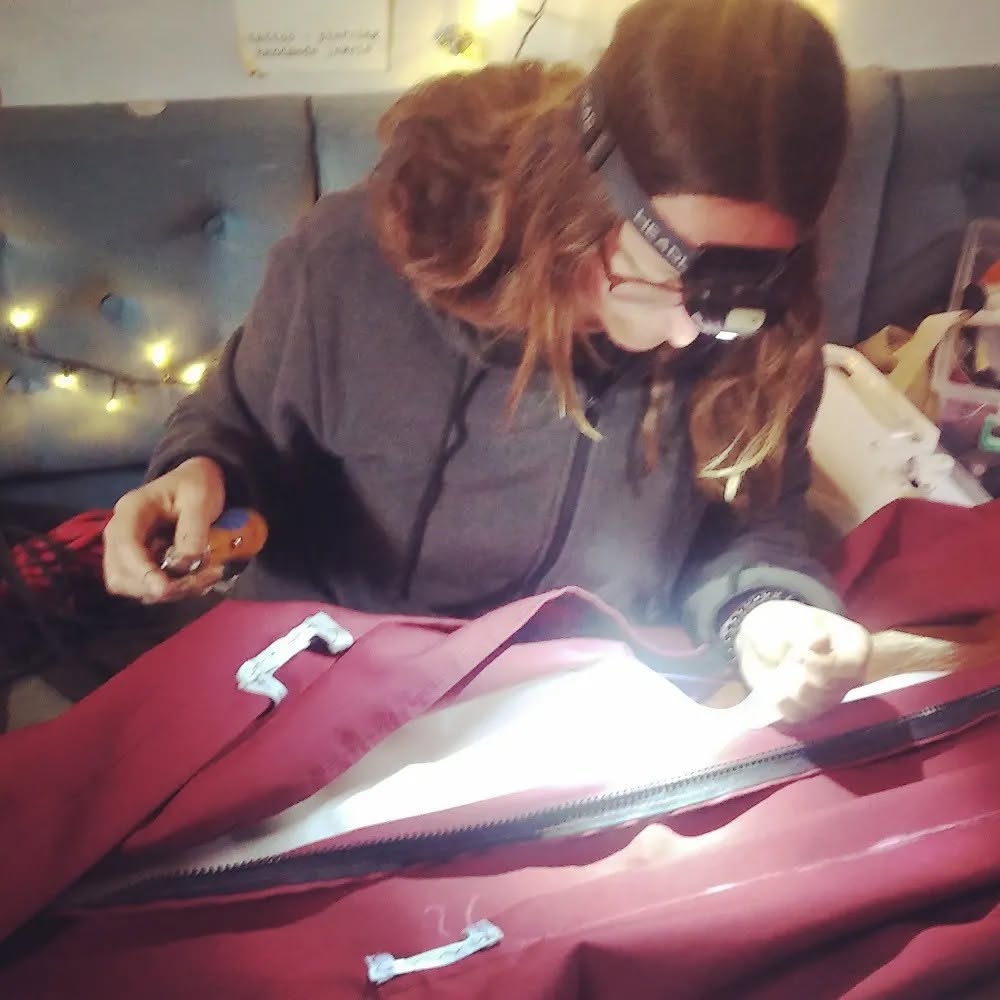 Woman sewing sailbog by hand in a 35 foot sailboat. 